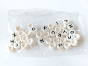 36 white tiles (1x1) with black letters inside a clear plastic bag.