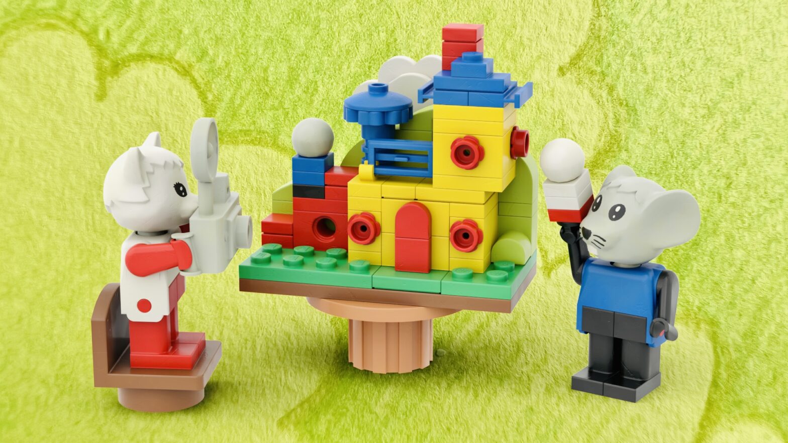 Cat minifigure pointing her camera at a microscale house. The mouse is holding a small brick-built version of his feline friend.